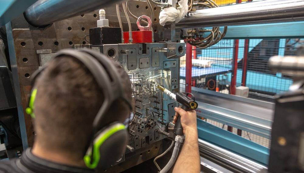 Operador trabalhando na automação de produção industrial com máquina de montagem de peças.
